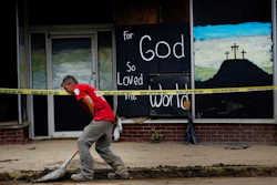 A volunteer shovels dirt and debris off of the main street in downtown Fleming-Neon, Ky., on Friday, Aug. 5, 2022. The previous week's massive flooding damaged much of the town.