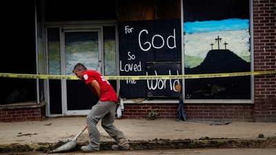A volunteer shovels dirt and debris off of the main street in downtown Fleming-Neon, Ky., on Friday, Aug. 5, 2022. The previous week's massive flooding damaged much of the town.
