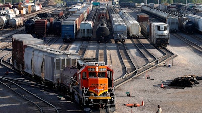 A BNSF rail terminal worker monitors the departure of a freight train, June 15, 2021, Galesburg, Ill.