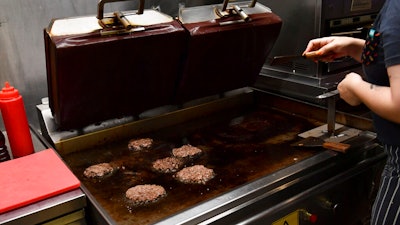 A worker cooks burgers at Zing Burger store in Budapest, Hungary, Monday, Sept. 12, 2022. Richard Kovacs, a business development manager for the Hungarian burger chain, said some of the chain's 15 stores have seen a 750% increase in electricity bills since the beginning of the year – leading to additional monthly costs of up to 1.5 million Hungarian forints ($3,840) per store.