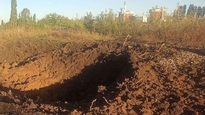 In this photo provided by the South Ukraine nuclear power plant, a crater left by a Russian rocket is seen 300 meter from the South Ukraine nuclear power plant, in the background, close to Yuzhnoukrainsk, Mykolayiv region, Ukraine, Monday, Sept. 19, 2022.