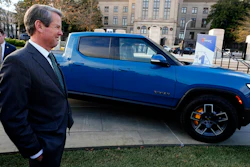 Georgia Gov. Brian Kemp smiles as he stands next to a Rivian electric truck during a ceremony to announce that the electric truck maker plans to build a $5 billion battery and assembly plant east of Atlanta projected to employ 7,500 workers, on Dec. 16, 2021, in Atlanta.