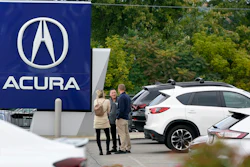 A salesman talks with customers in an Acura dealership lot in Wexford, Pa., on Sept. 29, 2022.