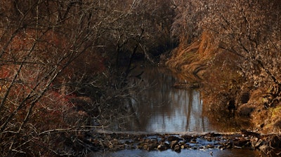 Water flows in Coldwater Creek on Thursday, Dec. 9, 2021, behind a row of homes at Belcroft Drive and Old Halls Ferry Road in Missouri's St. Louis County.