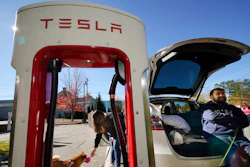 Janet Sanidad and her husband, Marc Sanidad, of Chantilly, Va., take a break to feed their dog while charging their Tesla, Wednesday, Oct. 19, 2022, in Freeport, Maine.