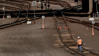A worker walks along tracks at a BNSF rail yard in Kansas City, Kan., Sept. 14, 2022.