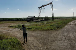 A youth plays near the machine where the sugar cane is weighed in the Lima batey, or neighborhood, in La Romana, where Central Romana Corporation, Ltd. operates its sugar operations in Dominican Republic, Nov. 17, 2021.