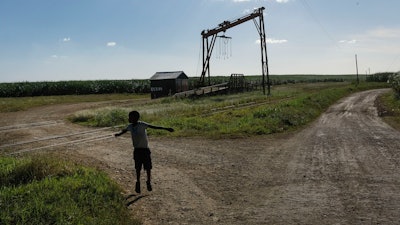 A youth plays near the machine where the sugar cane is weighed in the Lima batey, or neighborhood, in La Romana, where Central Romana Corporation, Ltd. operates its sugar operations in Dominican Republic, Nov. 17, 2021.