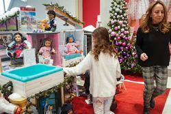 Jamie Cygielman, right, general manager and president at American Girl, leaves a youngster browsing the company's latest holiday showcase doll set, Friday, Dec. 2, 2022, in New York. Cygielman said roughly half its sales went to adults after a relaunch of the first six American Girl dolls in May 2021 to celebrate its 35th anniversary.