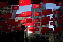 A man walks past Chinese and Hong Kong flags to celebrate the 25th anniversary of Hong Kong handover to China, in Hong Kong, on June 24, 2022. World Trade Organization arbitrators concluded Wednesday, Dec. 21, 2022, that the United States was out of line in requiring that products from Hong Kong be labeled as “Made in China,” a move that was part of Washington's response to a crackdown on pro-democracy protests there in 2019-2020.