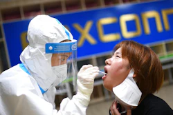 A medical worker takes a swab sample to test for COVID-19 from a worker at the Foxconn factory in Wuhan in central China's Hubei province Thursday, Aug. 5, 2021. Foxconn, the company that assembles Apple Inc.’s iPhones, has announced it is easing COVID-19 restrictions at its largest factory, in Zhengzhou, central China, that led thousands of workers to quit and drastically slowed production.