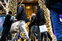 Shoppers carry shopping bags down Fifth Avenue, Monday, Dec. 19, 2022, in New York. After a two-year hiatus, holiday procrastinators are back this year, during a holiday season when retailers need them even more. Shoppers have been pulling back on buying and waiting for the best deals as inflation weighs on their shopping habits.