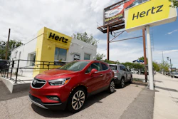 This May 23, 2020, photo shows rental vehicles parked outside a closed Hertz car rental office in south Denver.