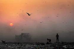 A thick blanket of smoke envelops young ragpickers searching for reusable material at a garbage dump in New Delhi, India.