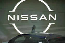 A staff walking near a Nissan logo at Nissan headquarters is seen though a window on May 12, 2022, in Yokohama near Tokyo. Nissan and Renault have changed their mutual cross-shareholdings to the same 15%, ironing out a source of conflict in the Japan-French auto alliance.