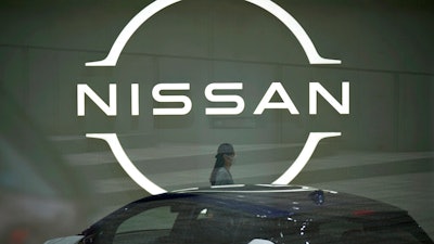 A staff walking near a Nissan logo at Nissan headquarters is seen though a window on May 12, 2022, in Yokohama near Tokyo. Nissan and Renault have changed their mutual cross-shareholdings to the same 15%, ironing out a source of conflict in the Japan-French auto alliance.
