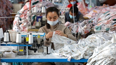 Workers wearing face masks sew fabrics at a textile factory in Huimin county in east China's Shandong province on Oct. 25, 2022. Chinese factory activity rebounded in January from three months of contraction, adding to signs the world’s second-largest economy might be recovering from a painful slump, an official survey showed Tuesday, Jan. 31, 2023.