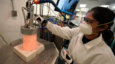 Research and development engineer Ravneet Kailey performs an experiment to produce steel without using carbon in a glowing lab cell, left, Wednesday, Jan. 25, 2023, at Boston Metal, in Woburn, Mass.