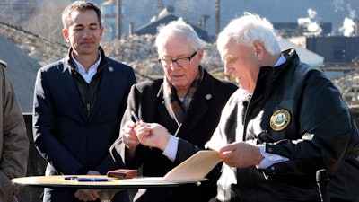 West Virginia Gov. Jim Justice, right, hands a pen used to sign House Bill 2882 to Weirton Mayor Harold 'Bubba' Miller, while Form Energy CEO Mateo Jaramillo watches.