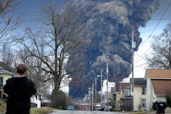 A man takes photos as a black plume rises over East Palestine, Ohio, as a result of a controlled detonation of a portion of the derailed Norfolk and Southern trains Monday, Feb. 6, 2023.