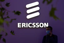 A man wearing a face mask talks on his smartphone near a booth from Swedish technology firm Ericsson at the PT Expo in Beijing, Wednesday, Oct. 14, 2020.