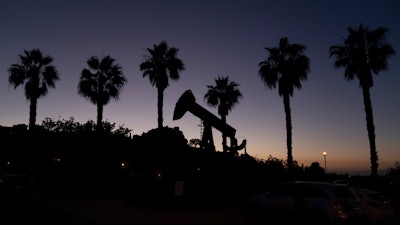 A pump jack sits idle in front of palm trees on June 9, 2021, in Signal Hill, Calif.