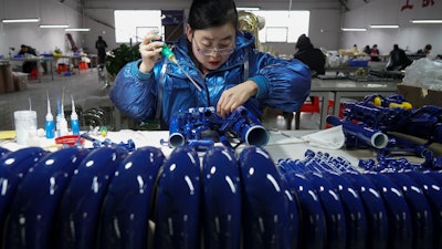 In this photo released by Xinhua News Agency, a worker assembles western musical instruments at a manufacturer factory in in Wuqiang County, north China's Hebei province on Feb. 23, 2023.