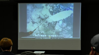 A spokesperson of the Tokyo Electric Power Company Holdings (TEPCO) shows photos captured by a robotic probe inside one of the three melted reactors at the tsunami-wrecked Fukushima nuclear power plant, during a news conference at the TEPCO headquarters in Tokyo, Tuesday, April 4, 2023.