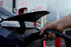 A motorist charges his electric vehicle at a Tesla Supercharger station in Detroit, Wednesday, Nov. 16, 2022. About half of U.S. adults say they are not likely to go electric when it comes time to buy a new vehicle, a new poll by The Associated Press-NORC Center for Public Affairs Research and the Energy Policy Institute at the University of Chicago shows.
