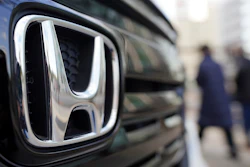 People walk near the logo of Honda Motor Company at a showroom Tuesday, Feb. 8, 2022, in Tokyo.