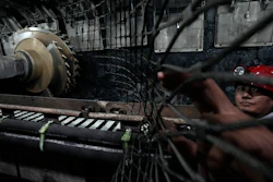 A miner pulls back the wire fence near the shearer at the mining face of Xiaobaodang Coal Mine near the city of Shenmu in northwestern China's Shaanxi province on Wednesday, April 26, 2023.