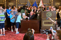 Democratic Minnesota Gov. Tim Walz jokes with kids as he shows off a bill he signed at the State Capitol in St. Paul, Minn., on Thursday, May 25, 2023, to establish a paid family and medical leave program in the state starting in 2026.