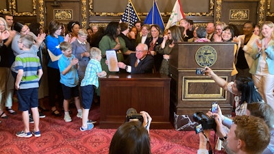 Democratic Minnesota Gov. Tim Walz jokes with kids as he shows off a bill he signed at the State Capitol in St. Paul, Minn., on Thursday, May 25, 2023, to establish a paid family and medical leave program in the state starting in 2026.