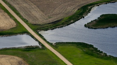 A road bisects a wetland on June 20, 2019, near Kulm, N.D. The Supreme Court has made it harder for the federal government to police water pollution. The decision from the court on Thursday, May 25, 2023, strips protections from wetlands that are isolated from larger bodies of water. It’s the second ruling in as many years in which a conservative majority has narrowed the reach of environmental regulations.