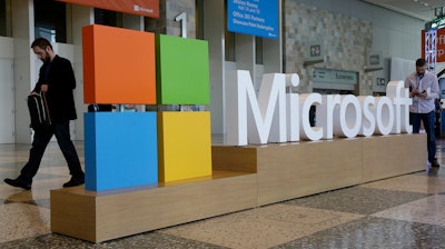 A man walks past a Microsoft sign set up for the Microsoft BUILD conference, April 28, 2015, at Moscone Center in San Francisco.