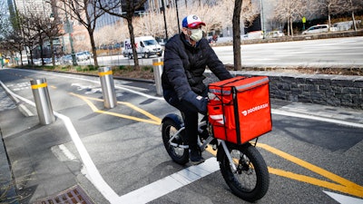 A delivery worker rides his bicycle along a path on the West Side Highway in New York, March 16, 2020.