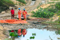 In this grab taken from video, workers stand by a container to collect oil spill waste, in Ogoniland, Nigeria, June 16, 2023. An oil spill at a Shell facility in Nigeria has contaminated farmland and a river. It's upended livelihoods in the fishing and farming communities of part of the Niger Delta, which has long endured environmental pollution caused by the oil industry.