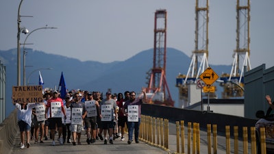Striking workers march as gantry cranes sit idle, Vancouver, July 6, 2023.