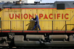 A maintenance worker walks on the side of a locomotive in the Union Pacific Railroad fueling yard in north Denver, Oct. 18, 2006.