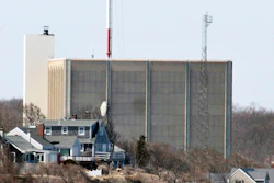 A portion of the Pilgrim Nuclear Power Station is visible beyond houses along the coast of Cape Cod Bay in Plymouth, Mass., March 30, 2011.