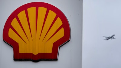 An aircraft passes a sign at a shell petrol station in London, Thursday, Feb. 2, 2023.