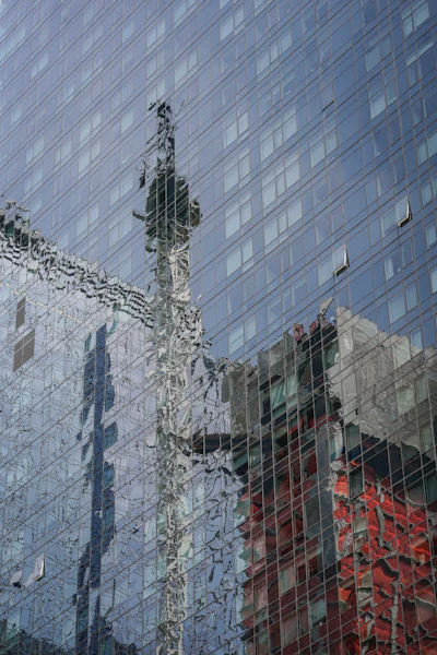 A glass paneled building reflects a hi-rise construction site crane, center, in the aftermath of a fire yesterday, that sent its extension arm plummeting to the street, Thursday July 27, 2023, in New York.