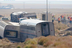 Workers stand near train tracks, Sept. 27, 2021, next to overturned cars from an Amtrak train that derailed near Joplin, Mont.