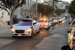 A Waymo driverless taxi stops on a street in San Francisco for several minutes because the back door was not completely shut, while traffic backs up behind it, on Feb. 15, 2023.