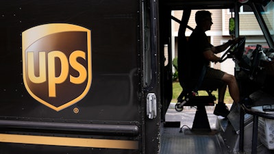 United Parcel Service driver Hudson de Almeida steers through a neighborhood in Haverhill, Mass., June 30, 2023.