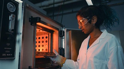 Purdue student Anna Murray places printed circuit board samples into an oven to test for stability and other important qualities in electronic components.
