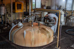 A technician looks through a lid into a culture vessel for yeast development at Bajaj Hindustan Sugar factory that produces ethanol, a type of biofuel, in Meerut, India, Wednesday, Aug. 23, 2023.