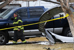 A North Metro firefighter walks past a large piece of a United airplane engine in the front yard of a home on Elmwood Street near E. 13th Avenue, Saturday, Feb. 20, 2021, in Broomfield, Colo.