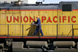 A maintenance worker walks on the side of a locomotive in the Union Pacific Railroad fueling yard, Denver, Oct. 18, 2006.