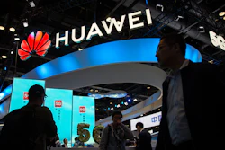 Attendees walk past a display for 5G services from Chinese technology firm Huawei at the PT Expo in Beijing, on Oct. 31, 2019.